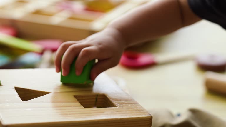 A baby is playing with a wooden toy block