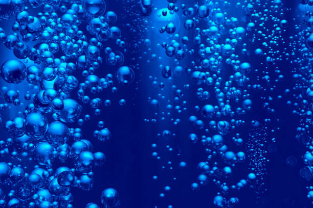 Defocus blurred transparent blue colored clear calm water surface texture with splashes and bubbles. Trendy abstract nature background. Water waves in sunlight with copy space. Blue watercolor texture