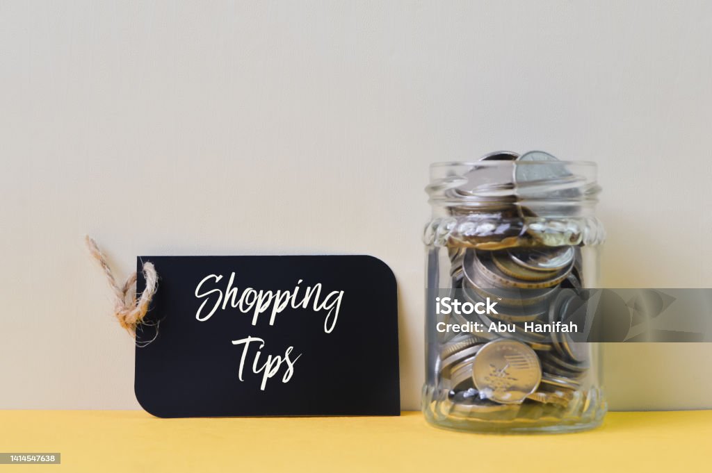 Stack of coins and label tag written with SHOPPING TIPS Advertisement Stock Photo