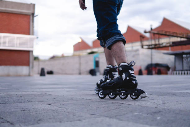 istock Roller skates rolling in the park. Boy walking with roller skates on an esplanade. Black roller skates rolling. 1414549861