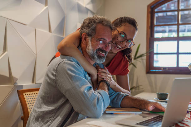 Father and his daughter work together on finances at home stock photo