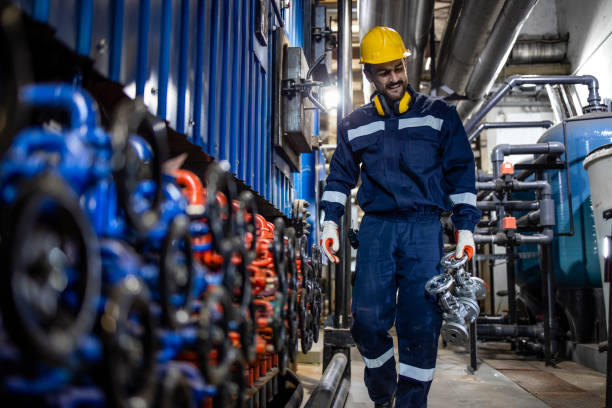 trabajador de fábrica reemplazando válvula industrial de alta presión en refinería de petróleo. - valve instrument of measurement indoors industry fotografías e imágenes de stock