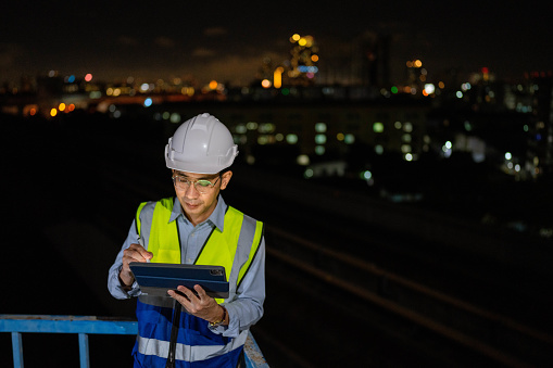 Male engineer is using a tablet to monitor operating procedures and record performance  for late-night operations.