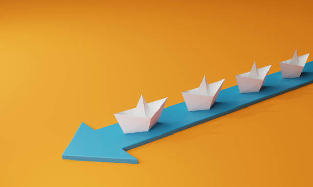 istock Paper boat and path on blue arrow on a yellow background 1414568877