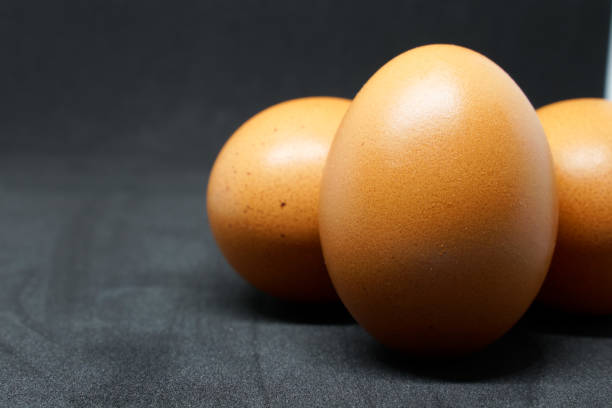 istock fresh chicken eggs laid out on a black background. 1414570900