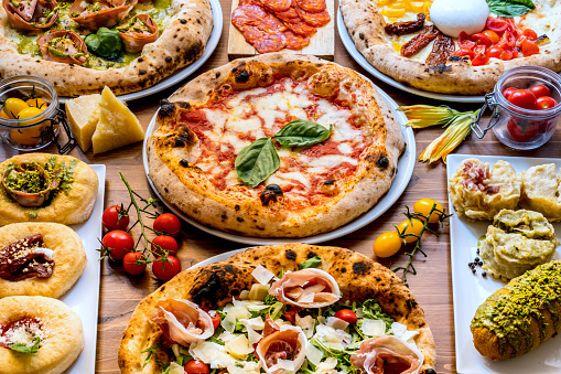 A delicious and tasty variety of Italian Pizzas of the original tradition of Naples. In the center, the famous Pizza Margherita, with fresh tomatoes, buffalo mozzarella and extra virgin olive oil, strictly cooked in a wood oven. In 2017 the art of Neapolitan pizza was declared by UNESCO as an Intangible Cultural Heritage. Image in High Definition format.