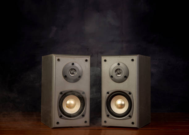 istock Two audio speakers with smoke in dark background room 1414580489