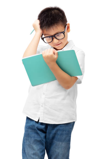 Kid with hand on head and holding book, thinking, doing homework, learning difficulties, wearing eyeglasses isolated on white background