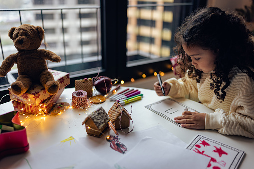 Little girl drawing Christmas cards at home