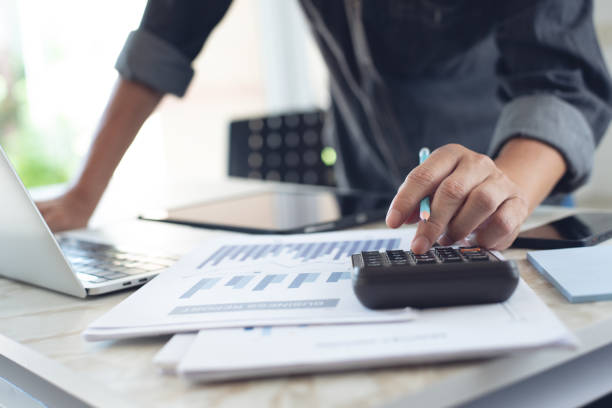 istock Business man working at office with digital tablet and laptop computer, using calculator to calculate financial report graph data documents on desk, close up. 1414588674