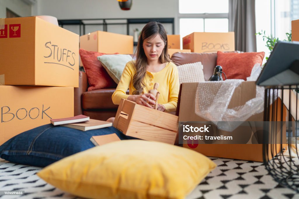happiness young adult asian female Woman packing things into boxes prepare moving from old place to new home with cheerful and happiness,home moving house booming ideas concept Decluttering Stock Photo