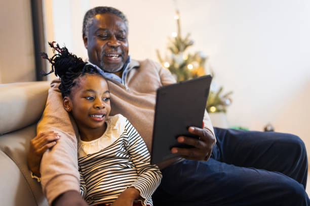 grand-père et petite-fille ayant l’appel vidéo - grandparent family reading inside of photos et images de collection