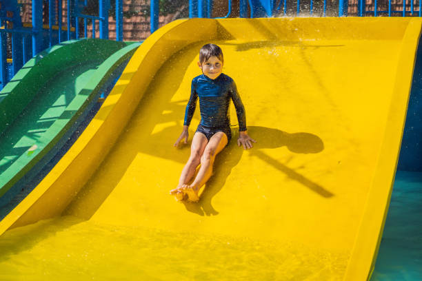 istock Smiling Young boy riding down a yellow water slide 1414599139
