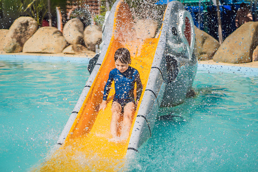 Smiling Young boy riding down a yellow water slide.