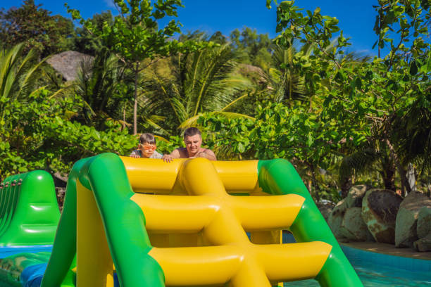 istock Dad and son go through an inflatable obstacle course in the pool 1414599182