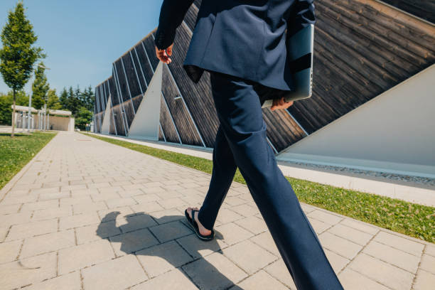 istock Rear view of politician walking with laptop on footpath against wall 1414602425