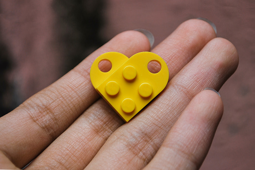 A heart shaped yellow brick above hand