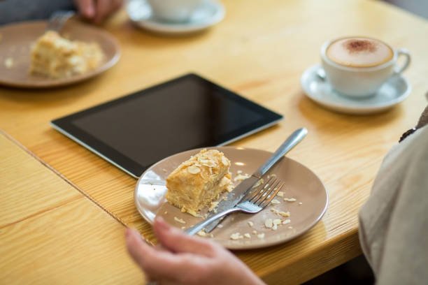 Cake and cutlery on plate. Tablet on a wood table.