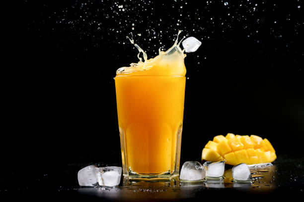 istock Fresh mango juice. A splash of mango cocktail on a black background. Ice cubes fall into the mango juice 1414608382