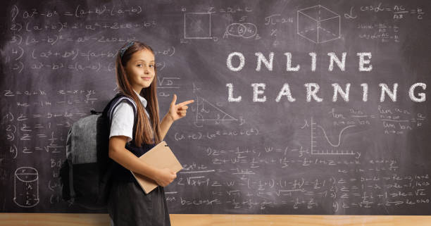 istock Schoolgirl with a backpack and book pointing at a blackboard with numbers and math and text online learning 1414609435