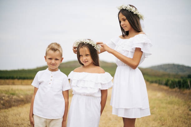 The girls in the photo embody love, tenderness, and spiritual upliftment. The main girl in a long dress stands among greenery, surrounded by twin sisters. The composition of three girls creates an image of celebration, harmony, and family support.