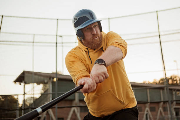 Overweight middle aged man on a diamond with a baseball bat