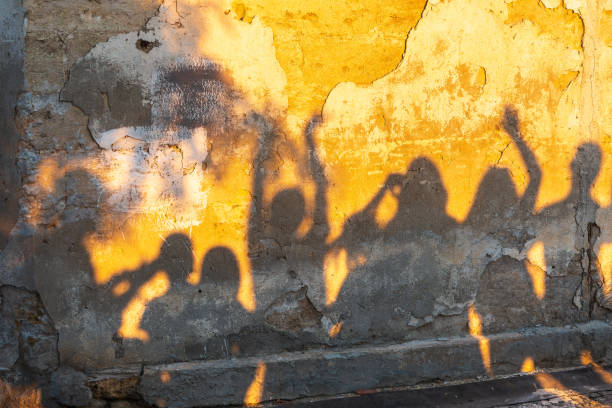 istock Shadows of dancing people on an old stone wall at sunset time. 1414611584