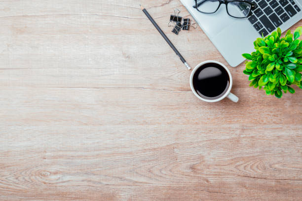 istock Work from home. desk office with laptop, blank notepad, coffee cup and pen on wood table. Flat lay top view copy spce. 1414612747