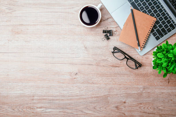 istock Work from home. desk office with laptop, blank notepad, coffee cup and pen on wood table. Flat lay top view copy spce. 1414612748