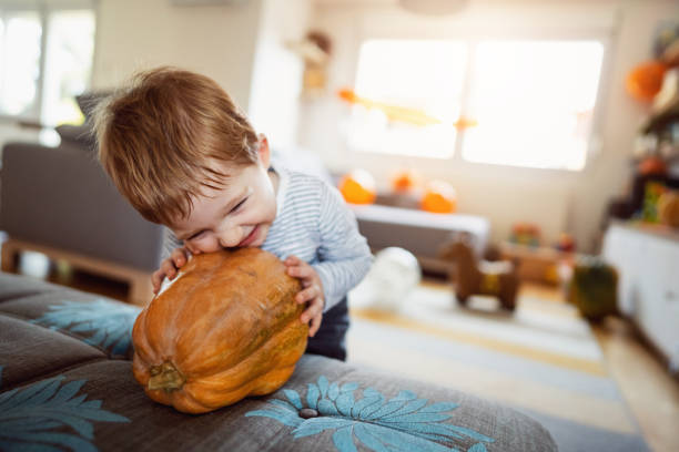 słodki kaukaski maluch bawiący się dynią, podczas świąt halloween - house halloween autumn candid zdjęcia i obrazy z banku zdjęć