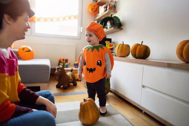 maluch przebrany za dynię, a matka za czarownicę, bawiący się podczas halloween - house halloween autumn candid zdjęcia i obrazy z banku zdjęć