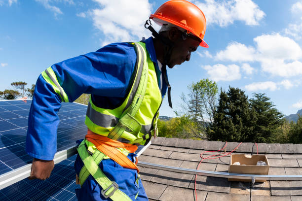 istock Side view man wearing safety harness carrying solar panel on roof 1414618882