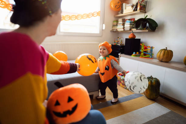 Toddler boy dressed as a pumpkin, for a Halloween playing with his mother stock photo