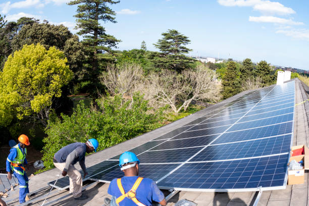 istock Wide shot workers installing solar panels surrounded by green trees tops 1414619054