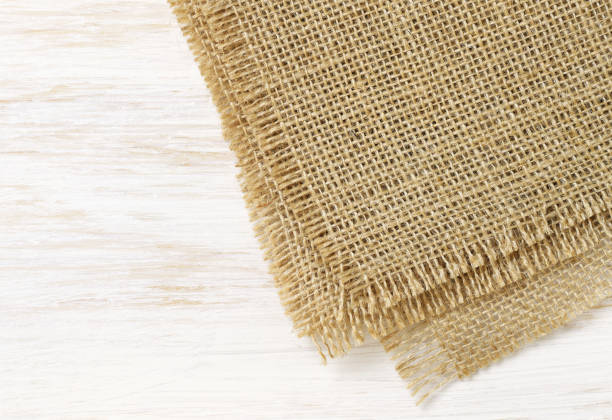 istock White painted wooden board and a canvas tablecloth on corner for background. Top view. 1414620360