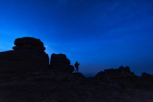 Female photographer standing on boulder before dawn in Iceberg Liang, China