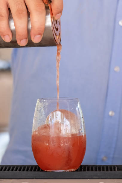 istock Professional bartender pouring cocktail into glass glass with shaker 1414624509