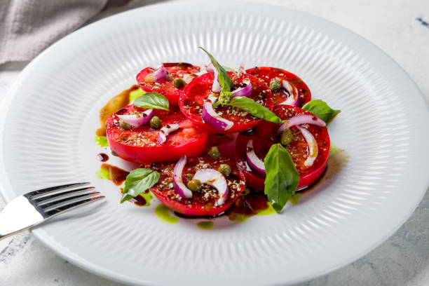 istock tomatoes bull's heart sliced with red onion on a white plate macro close up 1414624636