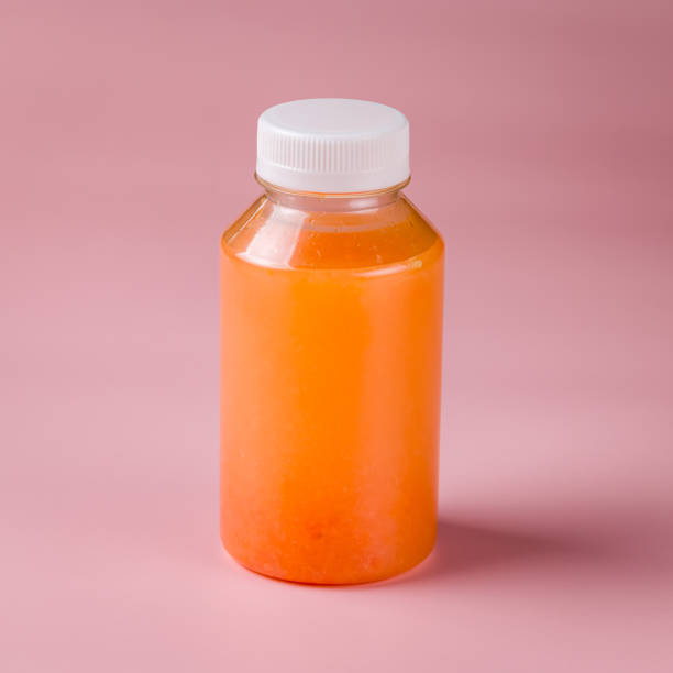 istock Fresh grapefruit juice in a bottle on pink background 1414625559
