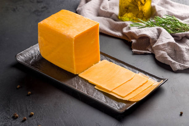 cheddar cheese sliced on black plate on dark table cheddar cheese sliced on black plate on dark table cheddar cheese stock pictures, royalty-free photos & images