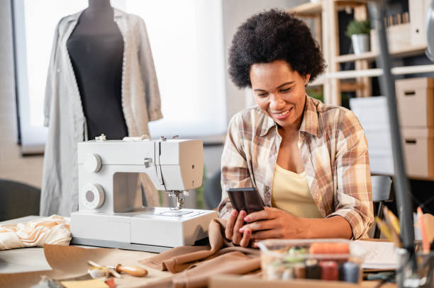 istock Young African-American entrepreneur woman working in her small workshop using a smartphone. Online banking apps for entrepreneurs 1414627344