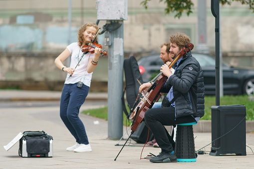 Moscow, Russia - September 13, 2021: Photography of cheerful music band playing music on the city street. They put on casual clothes, blue jeans. Occupation theme