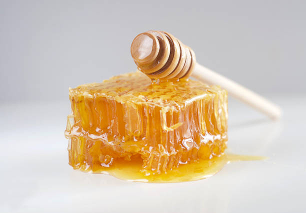 Honeycombs lie on the table, on top is a honey stick. Aesthetics