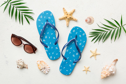 Summer travel concept. Flip flops, sunglasses and starfish on white. Top view on colored background.