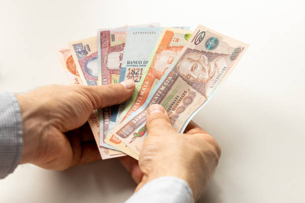 istock Guatemalan money, paper quetzals, held in hands against a bright table 1414638521