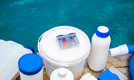High angle view of equipment for testing the quality of pool water and chemical cleaning products at the edge of swimming pool.