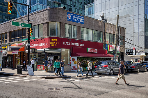 Queens, New York, NY, USA - July 5th 2022: People crossing the street at a street corner at Queens Plaza