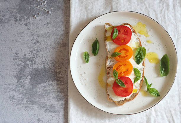 istock Sandwich with cheese, tomatoes and basil on a plate. 1414639540