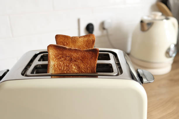 istock Modern white toaster and roasted bread slices toasts inside on wooden table in kitchen 1414639977