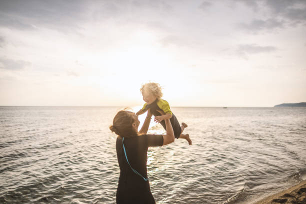 istock Surfer mum with her boy at the beach 1414640163